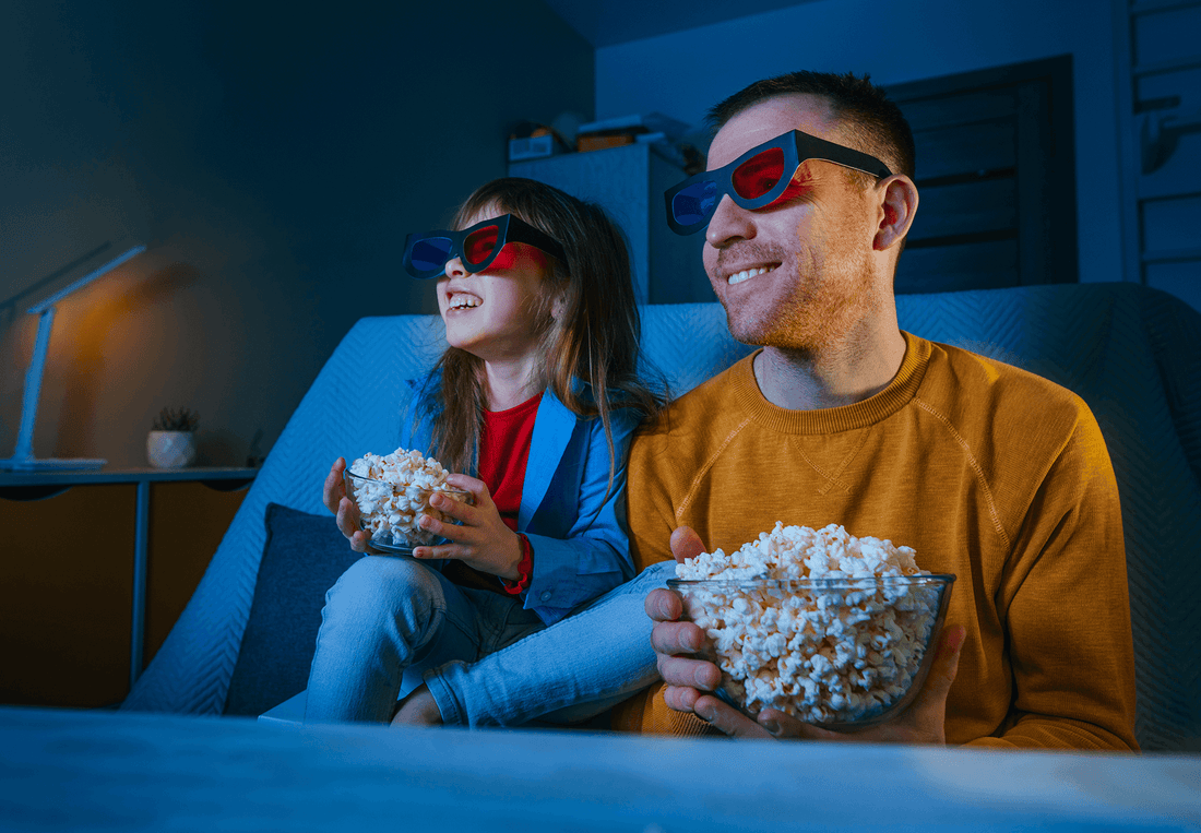 Young daughter and her father watching a movie at home