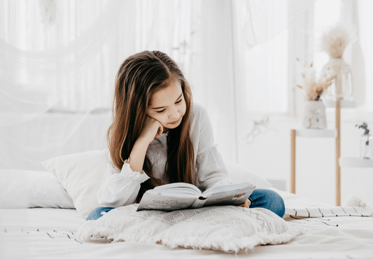 Young girl reading a book in a bright cozy living room