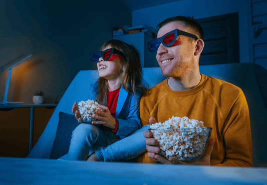 Young daughter and her father watching a movie at home